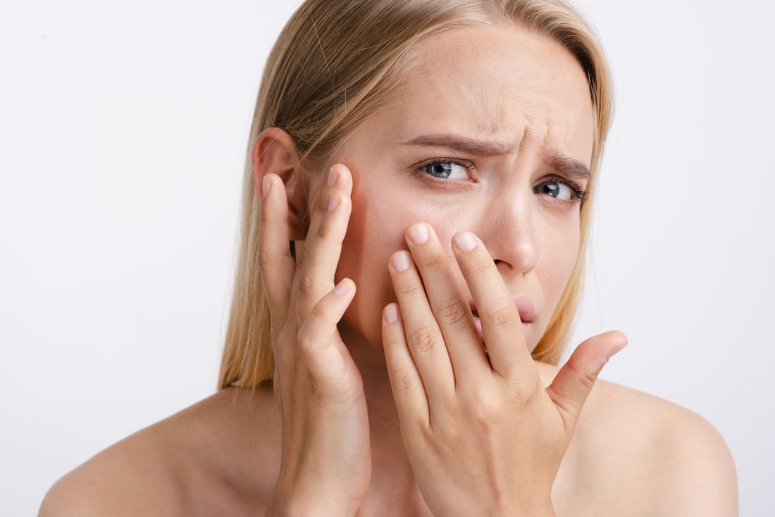 Femme regardant dans le miroir constate que sa peau visage est irritée