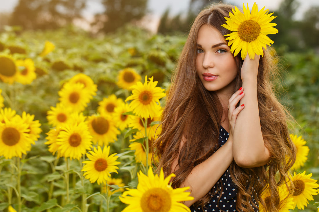 Une femme dans un champ de tournesols, car l'huile de tournesol nourrit les cheveux fins.