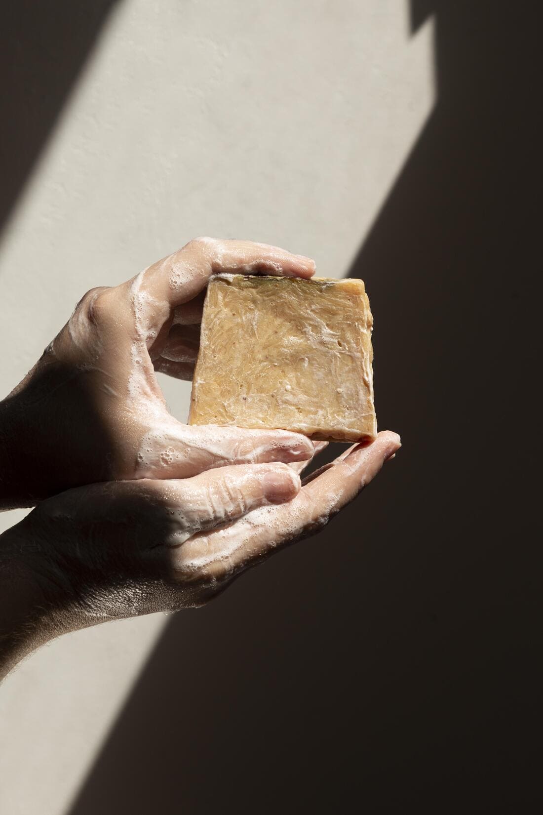 Une femme montre entre ses mains un savon naturel en train de mousser.